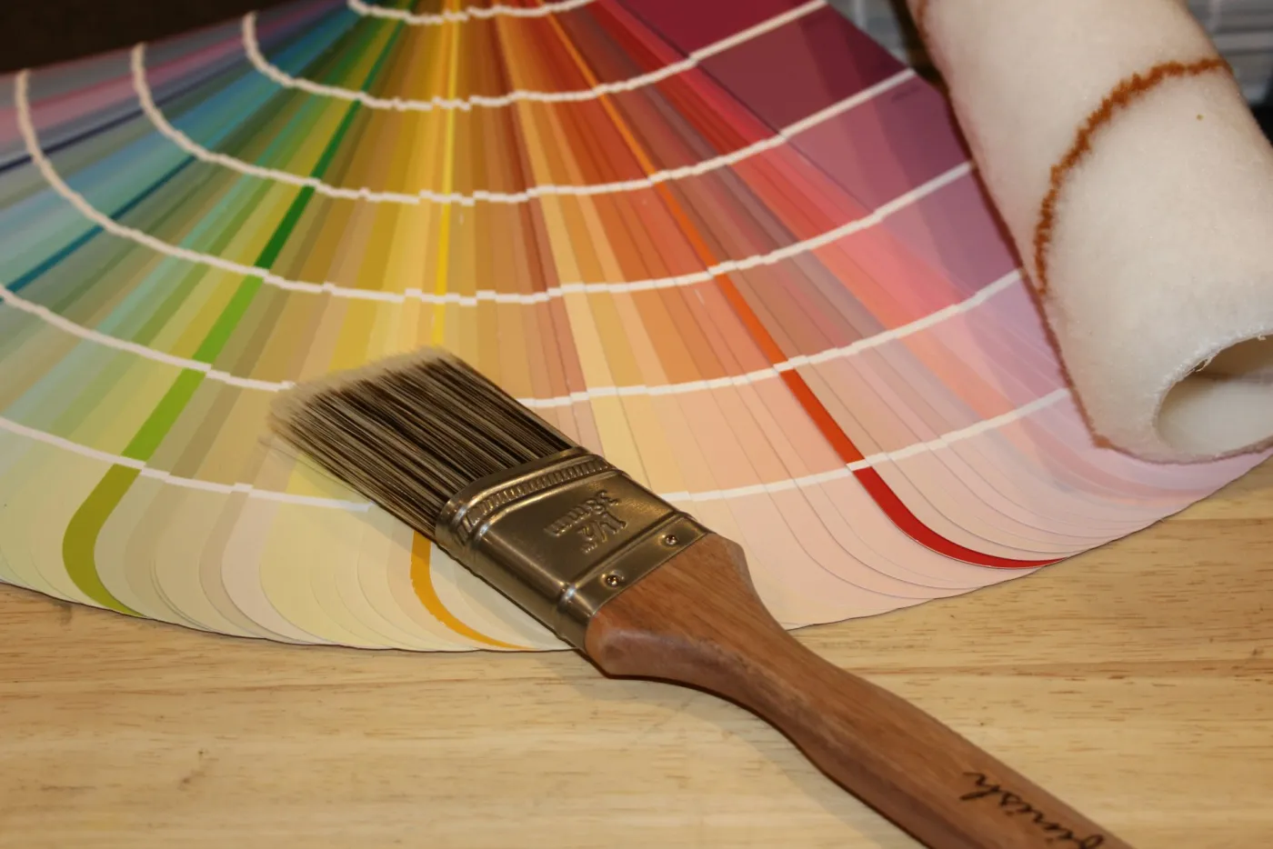 Paint brush, roller, and a fan of color swatches for custom color matching